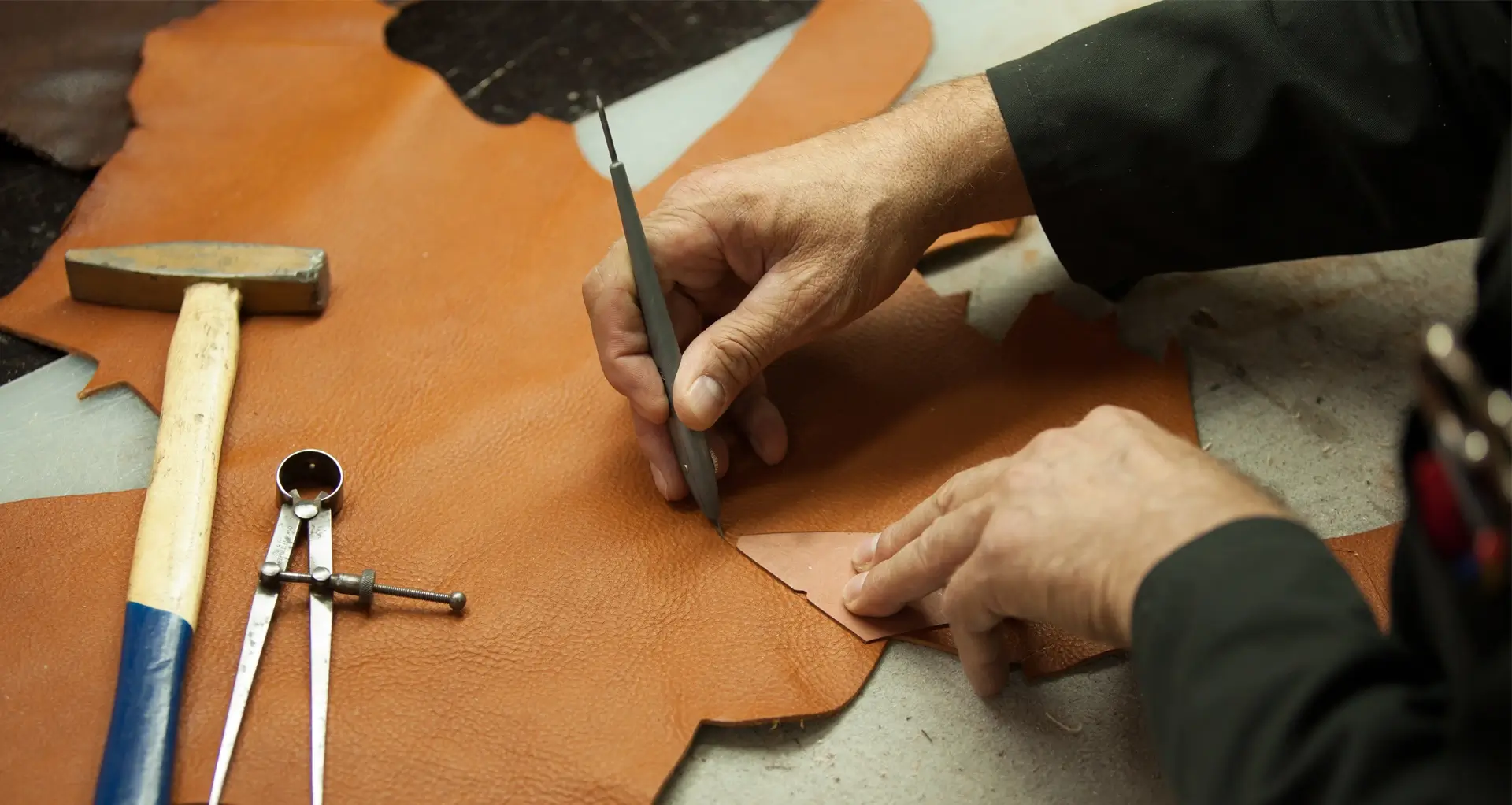 Мастер вырезает деталь из кожи